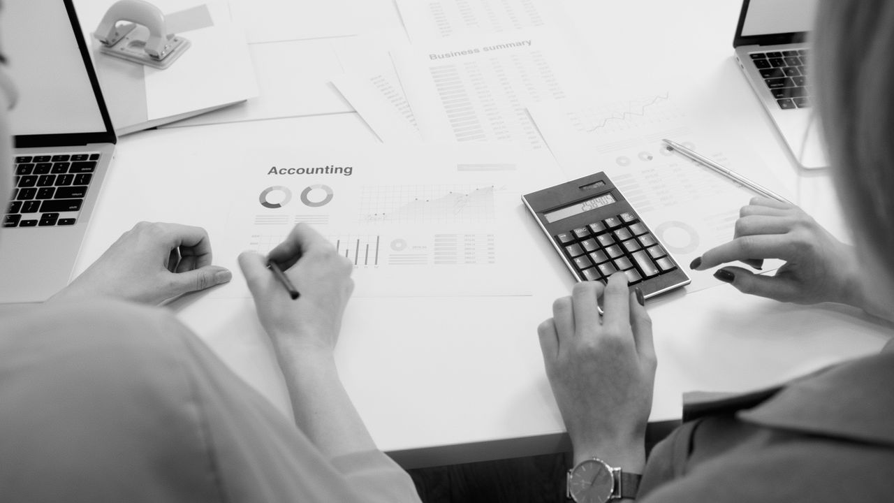 services-02 Black and white office scene featuring accounting documents, calculator, and laptops.