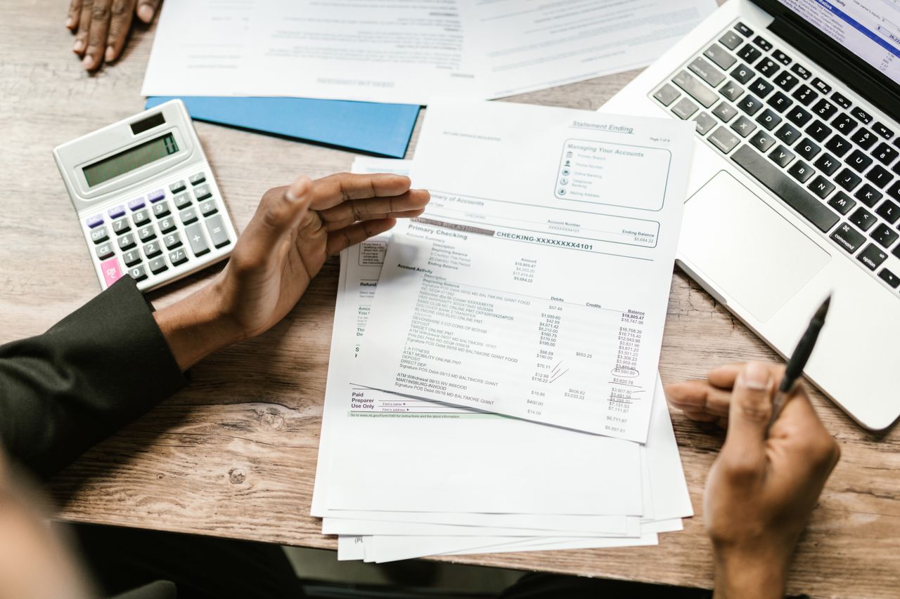 our-stories Hands holding financial documents with calculator and laptop on office desk, business analysis scene.